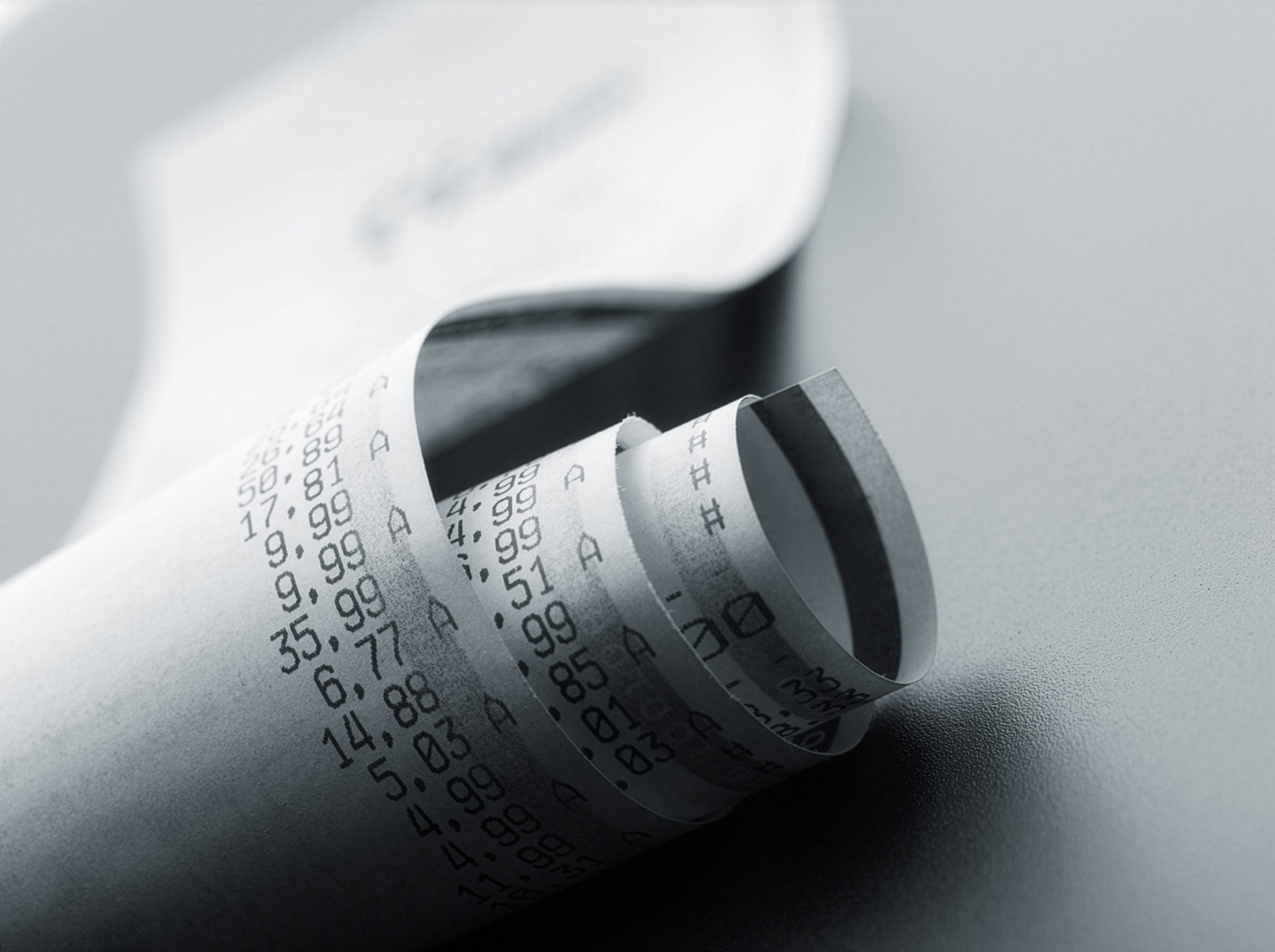 A long paper receipt curling across a wooden surface.